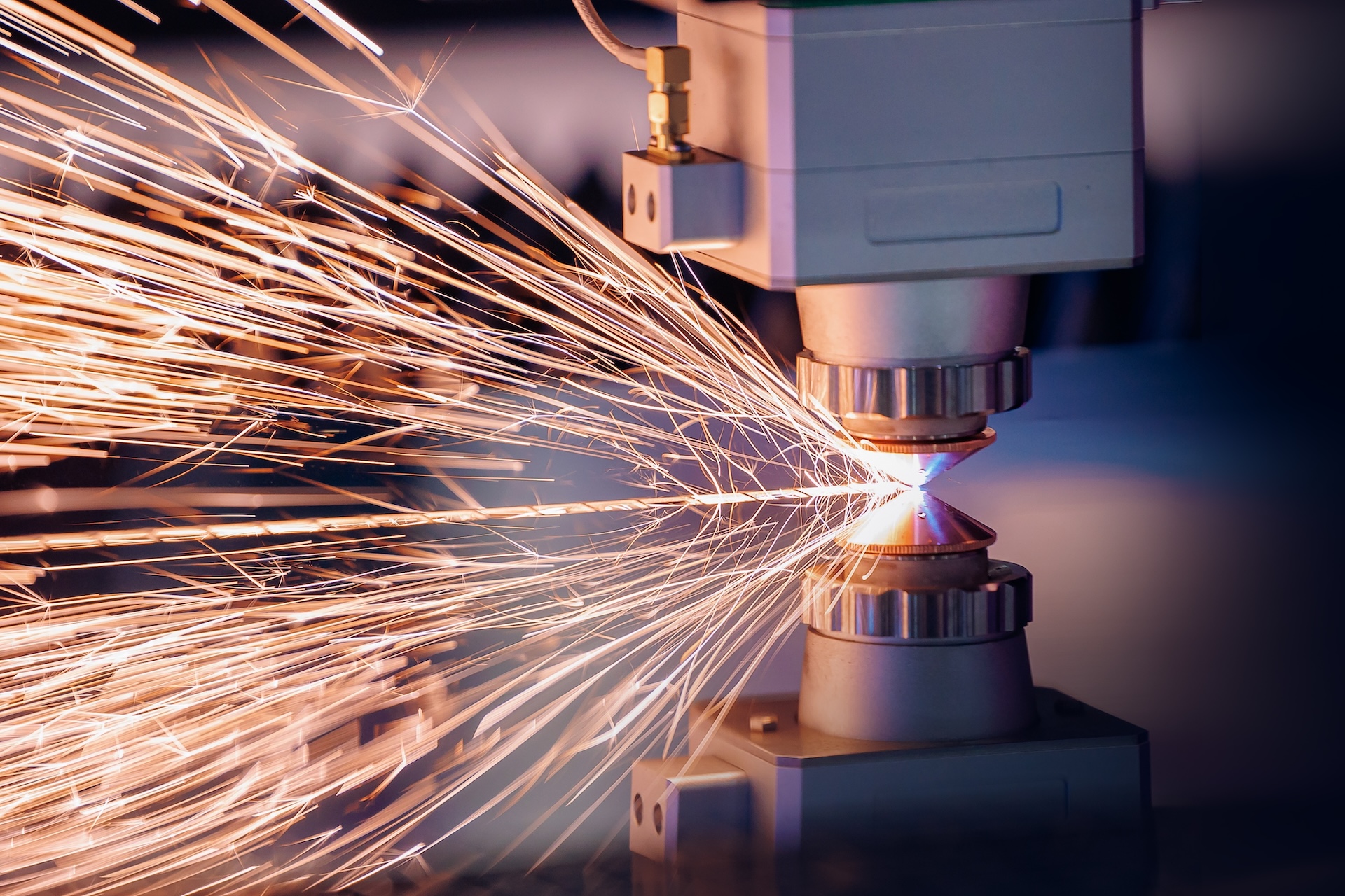 Close-up of sparks flying from a CNC laser cutting machine during metal fabrication.