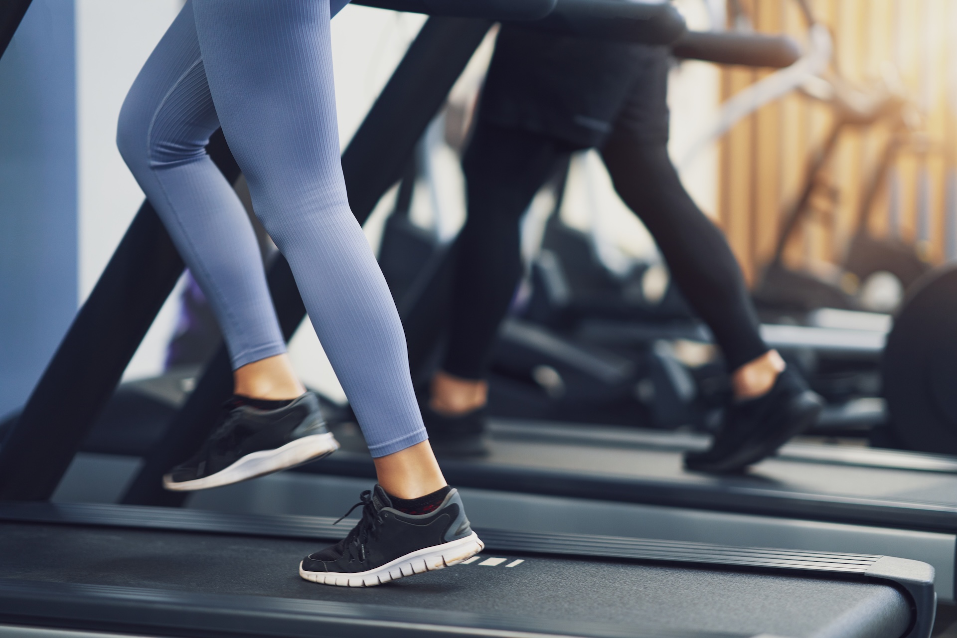 Close-up of people running on treadmills in a modern gym setting.