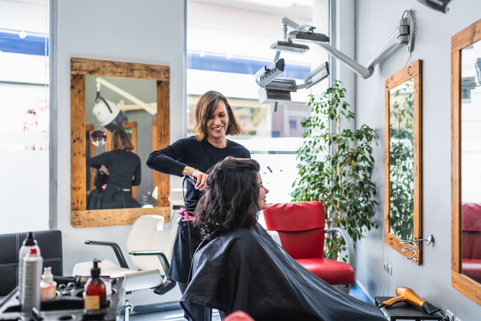 A scene in a hair dresser salon with a smiling woman cutting the hair of a customer