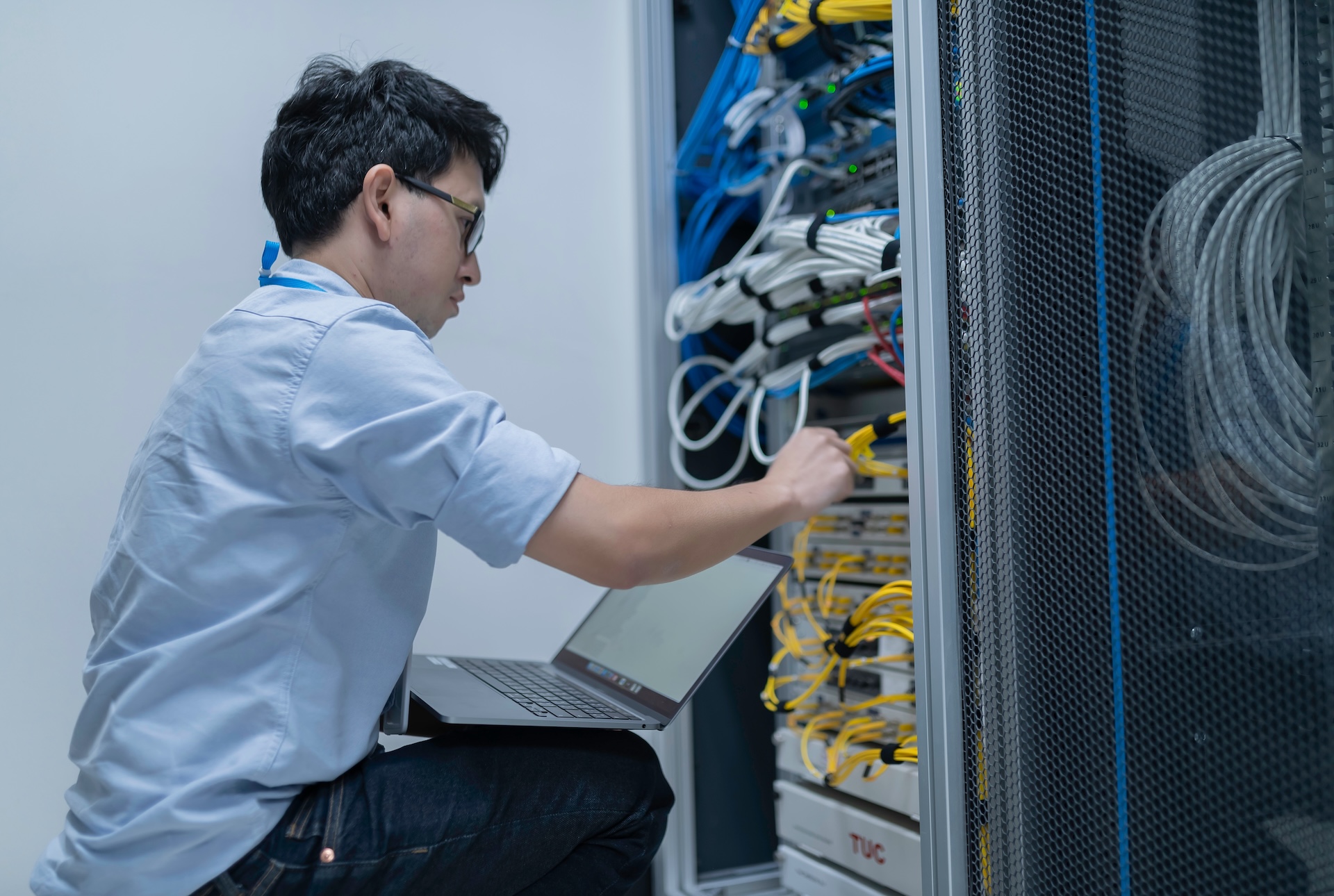 A graphic of a man holding a laptop looking at a server deck