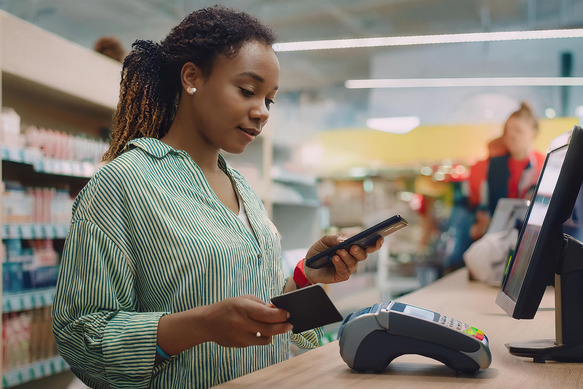 A woman in a shop looking at her phone phone to pay for her purchases