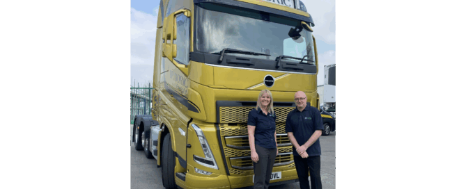 Full version of gold Volvo truck labeled 'ARMORIC' with two people smiling in front.