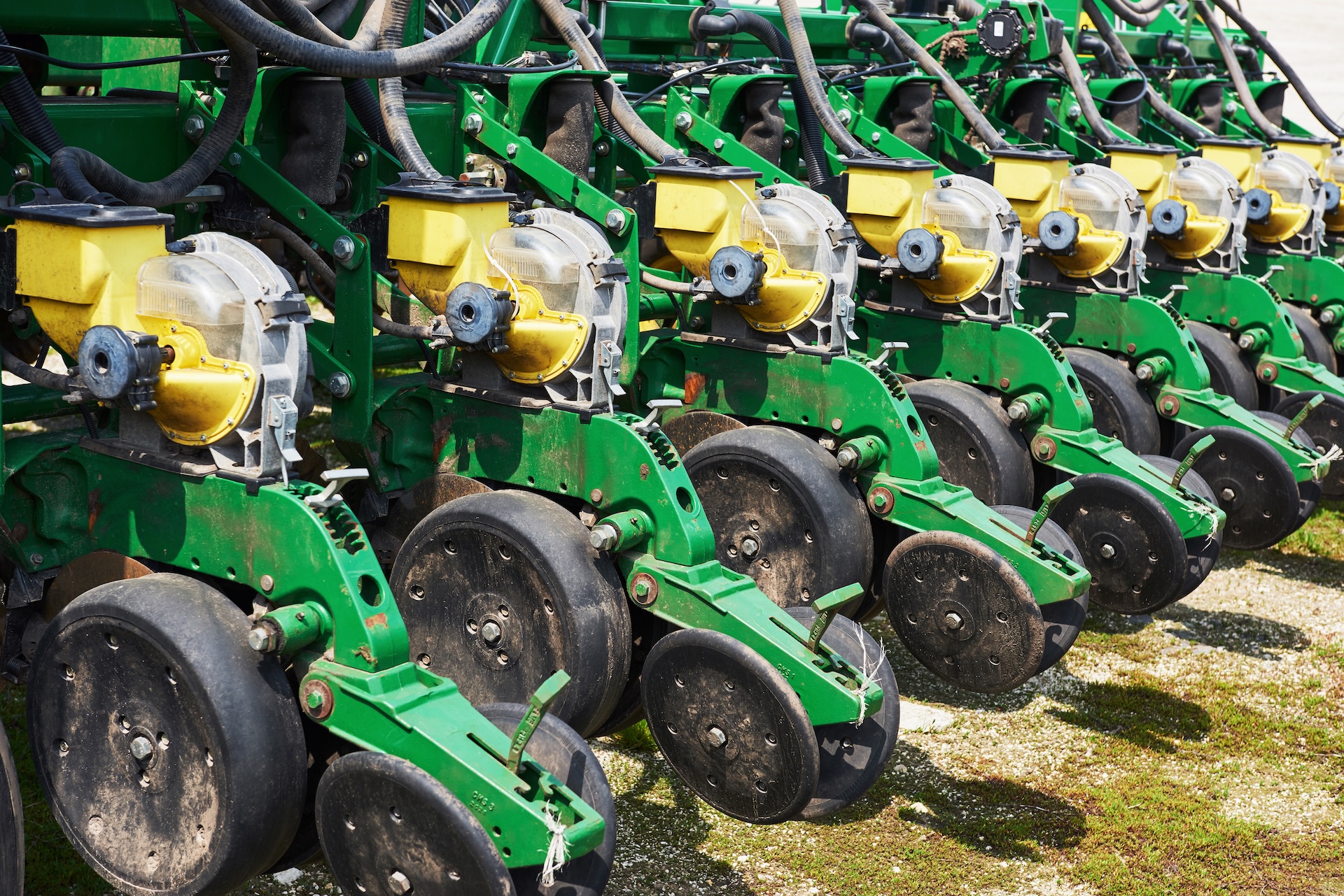 Close up of seeder attached to tractor in field. Agricultural machinery for spring works sowing A close up of green seeders attached to a tractor in field.