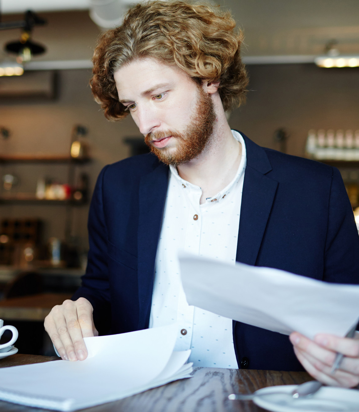 corptax2 Image of a man sitting at a desk in a coffee shop going through paperwork