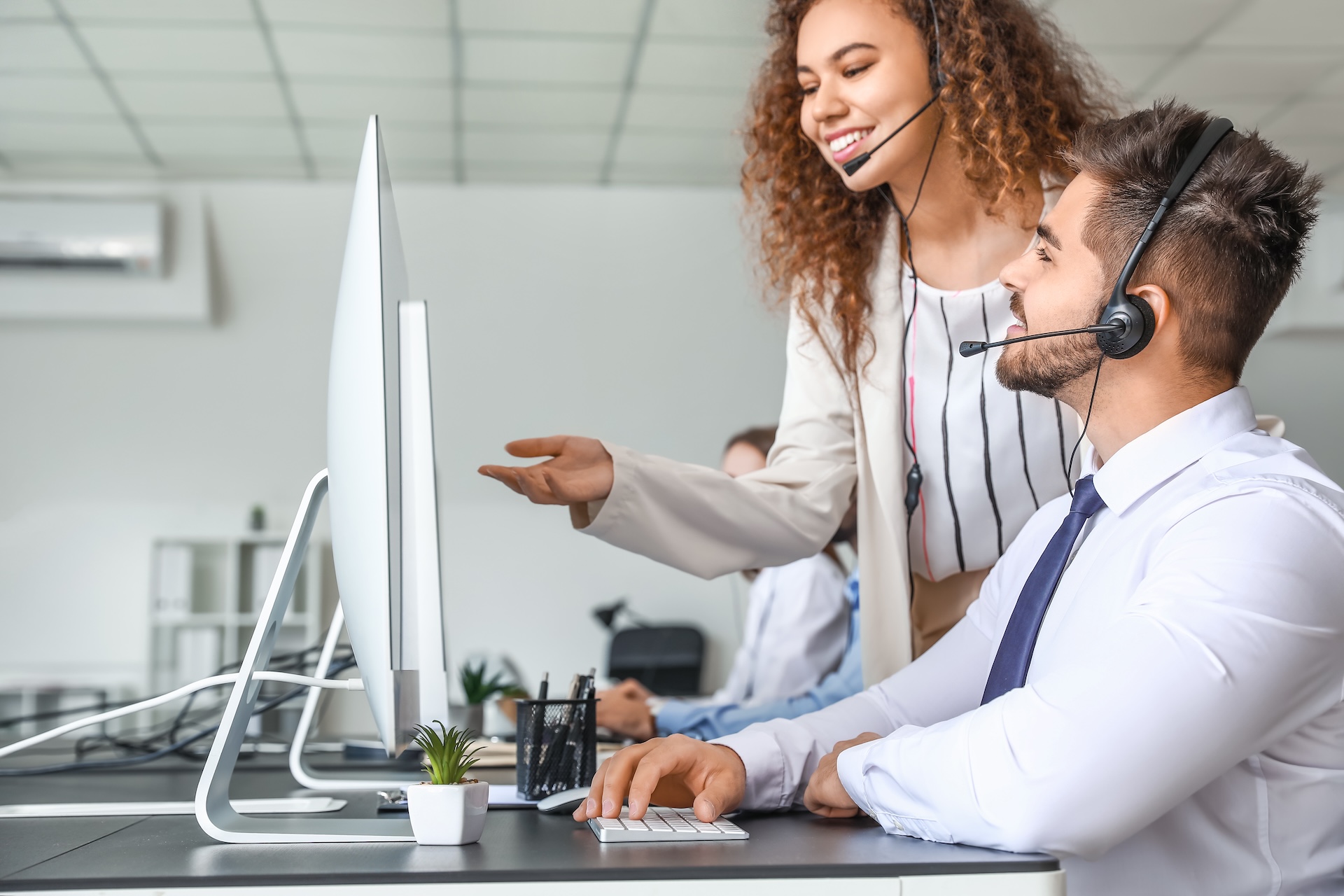 A image of two business people with headsets working in an office