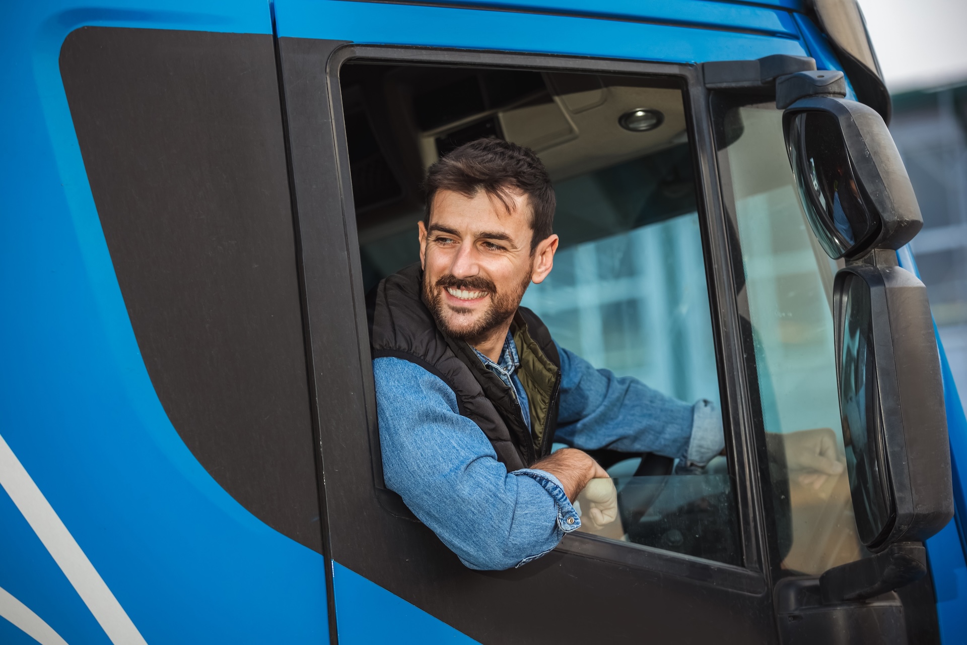 A young handsome man smiling out of the driver side window of his truck