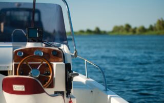 A white and brown motorboat docked near a calm waterfront, photographed from the behind