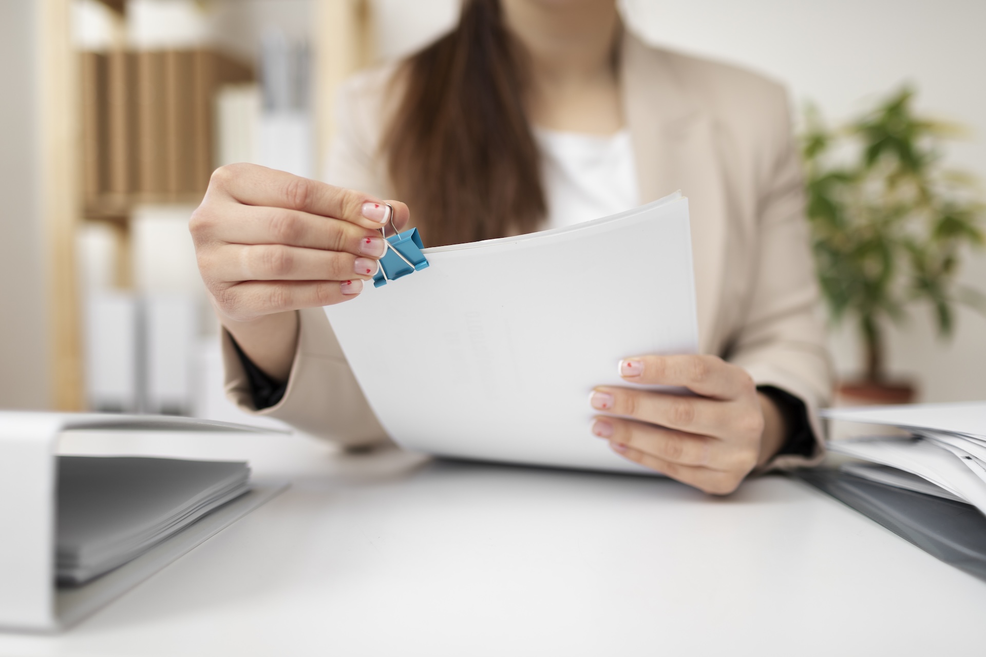 Young adult at a desk reviewing and organizing documents, indicating administrative or financial tasks.